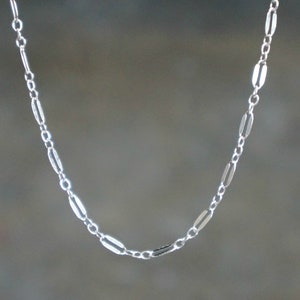 May include: A silver chain necklace with a delicate, oval-shaped link design.