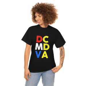 May include: Black t-shirt featuring the text "DC MD VA" in red, white, yellow, and blue. The shirt has a crew neck and is made of a soft fabric.