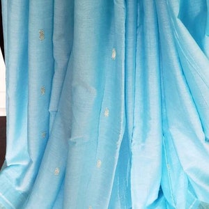 May include: A light blue cotton saree with a silver border and small silver embroidered dots throughout the fabric.