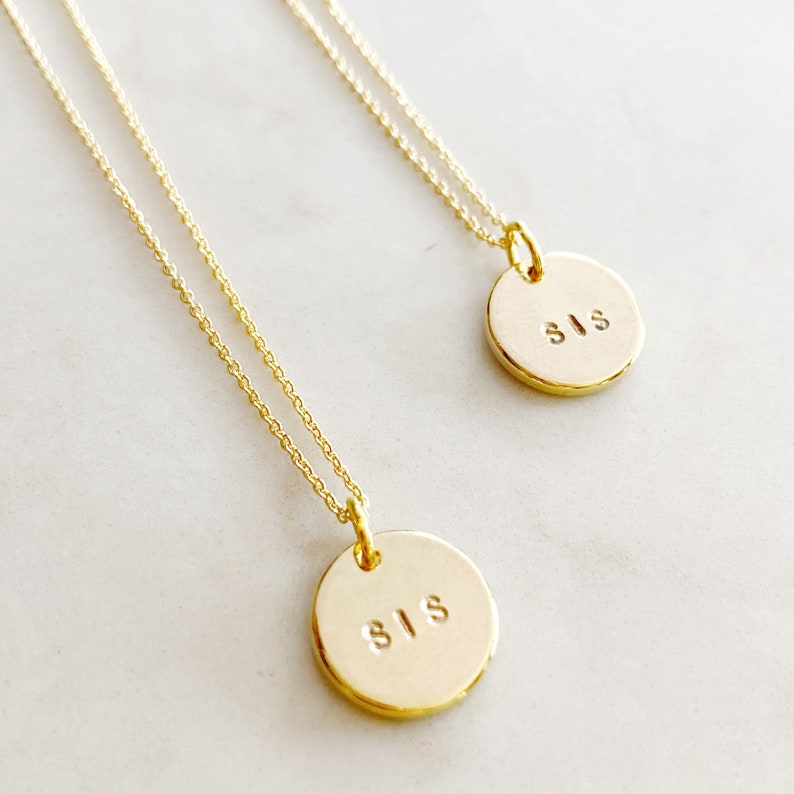 May include: Two gold necklaces with round pendants that say "SIS" on them.