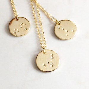 May include: Three gold necklaces with circular pendants featuring different constellations. Each pendant has small, sparkling diamonds representing the stars in the constellation.