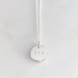 May include: A silver necklace with a round pendant that says "SIS" on it.