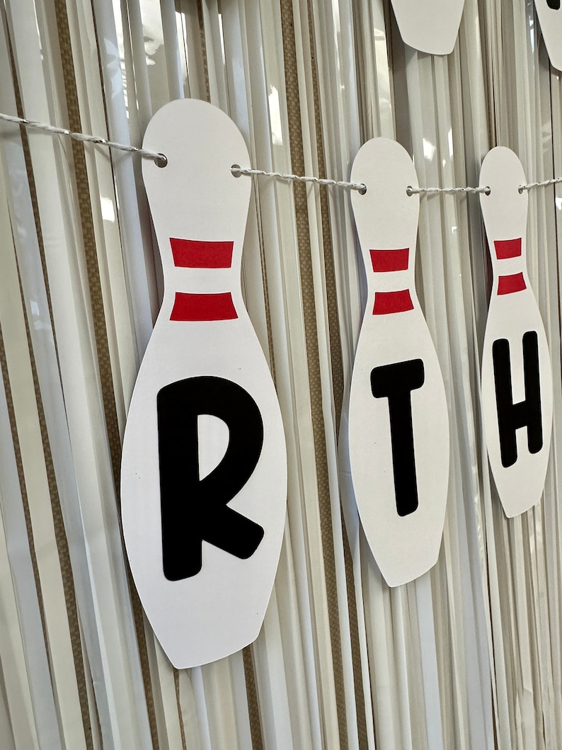 May include: White and red bowling pin shaped banner with the word "BIRTH" in black letters.