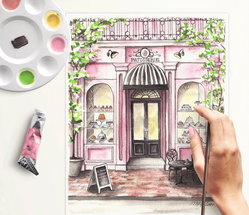 May include: Watercolor painting of a pink storefront with a sign that reads "Patisserie". The storefront has a large window display filled with pastries and a black door with a glass window. There is a small table and chairs outside the store.