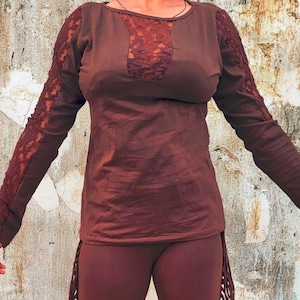 Könnte beinhalten: Ein braunes Langarm-Top mit Spitzendetails an den Ärmeln und am Ausschnitt. Das Top wird mit passenden braunen Leggings kombiniert. Das Outfit hat einen Bohemian-Stil.