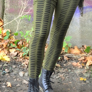 Puede incluir: Leggings verdes con recortes, usados con botas negras de cordones. Los leggings tienen un diseño único con múltiples filas de pequeños recortes ovalados.