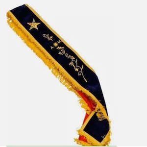 May include: A blue and red sash with gold fringe and embroidered details, including a star and a vine with flowers. The sash is used in a Masonic ceremony.