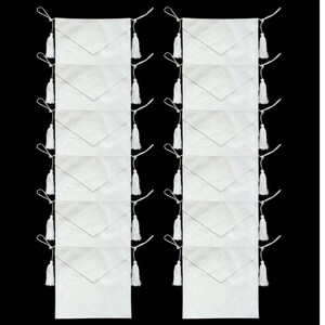 May include: A set of 10 white fabric envelopes with white tassels. The envelopes are lined up in two rows of five, with the tassels hanging down from the top of each envelope.