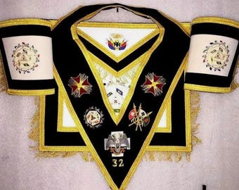 Conjunto de indumentaria masónica del Rito Escocés de 32º grado: delantal, cuello y puños de francmasón en negro y dorado, e indumentaria ceremonial bordada.