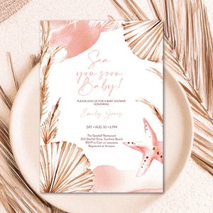 May include: A rectangular baby shower invitation card featuring watercolour illustrations of a pink starfish, dried palm leaves, and pampas grass. The text reads: Sea you soon Baby! Please join us for a baby shower honouring Emily Jones, Sat Aug 30, 6 PM.