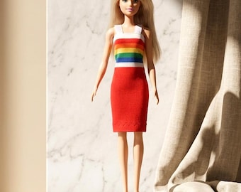 May include: A blonde doll wearing a sleeveless dress with a horizontal rainbow-striped bodice and a solid red skirt. The doll has straight hair, a neutral facial expression, and is wearing red platform shoes. The figure stands in an upright position.