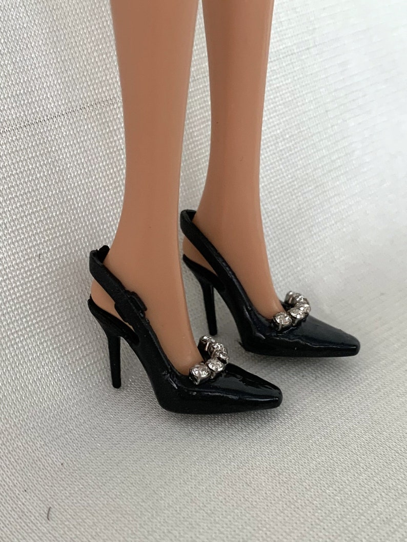 May include: A pair of black high-heeled shoes with a slingback strap and rhinestones on the toe.