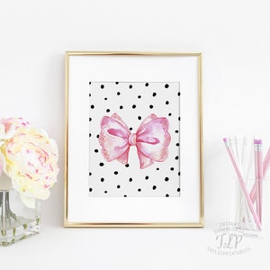May include: A printable art print featuring a pink bow with a white polka dot background. The bow is drawn in a watercolor style and has a delicate, feminine look.