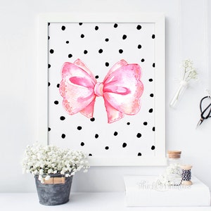 May include: A pink watercolor bow with a white polka dot background. The bow has a scalloped edge and is tied with a white ribbon. The background is white with black polka dots.