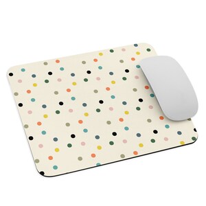 May include: A beige mouse pad with a repeating pattern of colorful polka dots. The dots are in shades of black, yellow, orange, pink, blue, and green.
