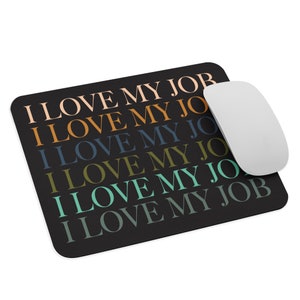 Op de afbeelding: Een zwarte muismat met de tekst "I LOVE MY JOB" die in verschillende kleuren wordt herhaald, waaronder roze, oranje, blauw, groen en turquoise.
