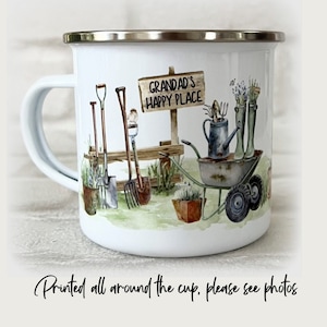 May include: White enamel mug with a silver rim and handle. The mug features a watercolour illustration of gardening tools, a wheelbarrow, and a sign that reads "GRANDAD'S HAPPY PLACE."