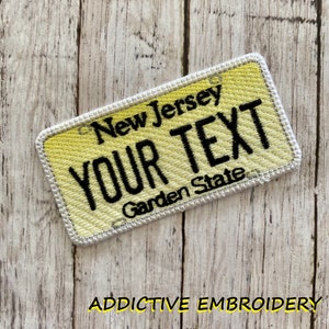 May include: Yellow embroidered patch with a white border, resembling a New Jersey license plate. The patch reads "New Jersey" and "YOUR TEXT" with the words "Garden State" below.