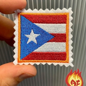 Può includere: Toppa ricamata a forma di francobollo, raffigurante la bandiera di Porto Rico. Il disegno comprende un triangolo blu con una stella bianca e strisce rosse e bianche. La toppa ha un bordo bianco con un bordo smerlato.