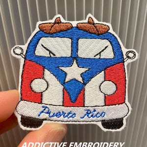 Può includere: Toppa ricamata raffigurante un furgone dei cartoni animati nei colori della bandiera portoricana: rosso, bianco e blu. Il furgone ha una stella bianca e la scritta "Puerto Rico" in blu. La toppa include anche la scritta "ADDICTIVE EMBROIDERY".