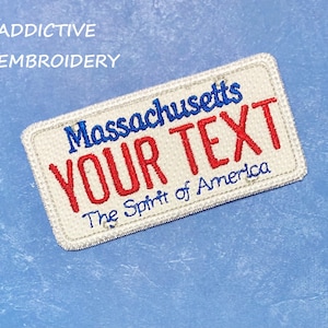 May include: White embroidered patch with blue and red stitching. The patch is shaped like a number plate and reads "Massachusetts" at the top, "YOUR TEXT" in red letters in the middle, and "The Spirit of America" at the bottom.
