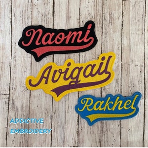Könnte beinhalten: Drei gestickte Patches mit den Namen "Naomi", "Avigail" und "Rakhel" in einer kursivschriftlichen Schriftart. Die Patches befinden sich auf einem Holzgrund. Der Text "Addictive Embroidery" befindet sich am unteren Rand des Bildes.