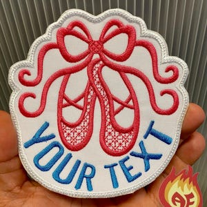 Könnte beinhalten: Gestickter Aufnäher mit roten Ballettschuhen und einer Schleife sowie dem blauen Text "YOUR TEXT". Der Aufnäher hat einen weißen Hintergrund und einen gewellten Rand. Ein kleines Flammenlogo befindet sich in der Ecke.