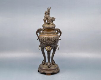 May include: A bronze incense burner with a lion finial and intricate carvings. The burner has three legs and a round base.