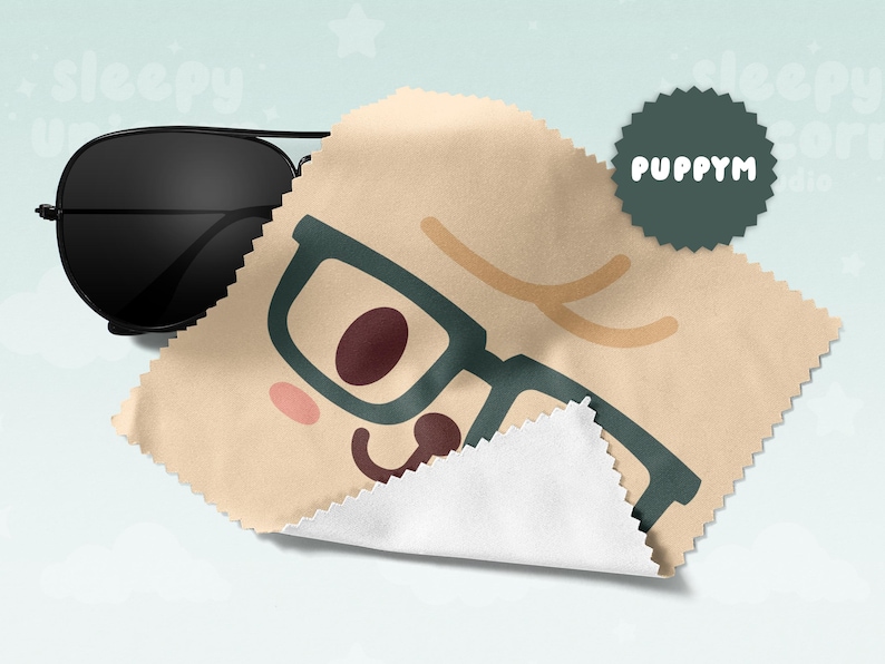 May include: Black aviator sunglasses rest on a tan microfiber cloth with a cartoon face design. The cloth features teal-framed glasses, a brown nose, and a smiling mouth. A dark green circular logo with the text "PUPPYM" is also visible.