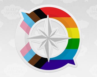 May include: A circular sticker featuring a white compass rose in the center. The background is divided into two sections: the left side displays the trans pride flag colors of light blue, pink, and white, while the right side shows the rainbow pride flag.