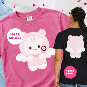 May include: A pink t-shirt featuring a cartoon angel bear design on the front and back. The front of the shirt has the text "MORE COLORS" in a white circle. The back of the shirt has the text "+BACK PRINT!" in a pink circle.