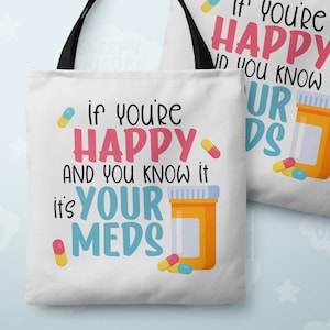 May include: White tote bag with black handles featuring a colorful graphic with the text "If you're happy and you know it, it's your meds". The graphic includes a pill bottle and pills.