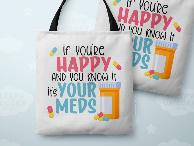 May include: White tote bag with black handles featuring a colorful graphic with the text "If you're happy and you know it, it's your meds". The graphic includes a pill bottle and pills.