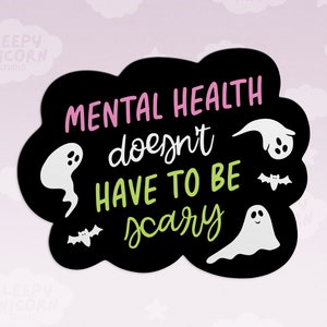 May include: A black sticker with the text "MENTAL HEALTH doesn't HAVE TO BE scary" in pink and green. The sticker features white ghost and bat illustrations. The background is a light pink with white clouds.