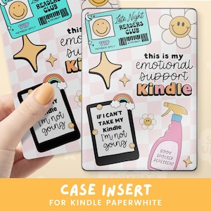 May include: A pink and white case insert for a Kindle Paperwhite with a rainbow, a smiley face, and the text "this is my emotional support Kindle".