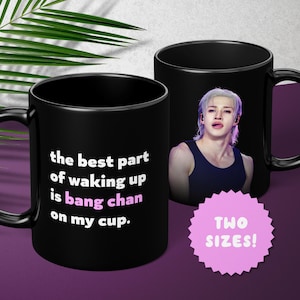 May include: Two black coffee mugs. One mug has the text "the best part of waking up is bang chan on my cup." The other mug has a picture of a person. A pink sticker says "TWO SIZES!"