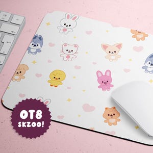 May include: White mousepad with cartoon animal characters, hearts, and stars. The mousepad has a white mouse and keyboard next to it. The mousepad has the text "OT8 SKZOO!" on a purple badge.