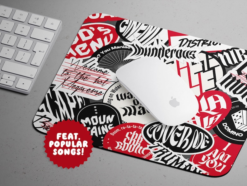 May include: A rectangular mousepad with a collage of red, black, and white sticker-like designs and text. A white computer mouse rests on the pad, next to a white keyboard. The mousepad features the text "FEAT. POPULAR SONGS!"