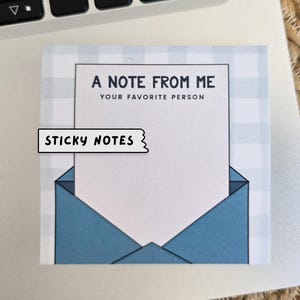 Puede incluir: Un bloc de notas adhesivas con estampado de cuadros vichy azul y blanco con un diseño de sobre blanco y el texto "A Note From Me Your Favorite Person" y "Sticky Notes" en negro.