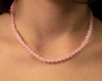 May include: A delicate pink rose quartz beaded necklace. The necklace is made of small, round beads that are strung together on a thin chain.