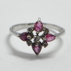 Peut inclure: Une bague en argent avec un groupe de pierres précieuses roses et de plus petites pierres précieuses blanches dans un motif en étoile.