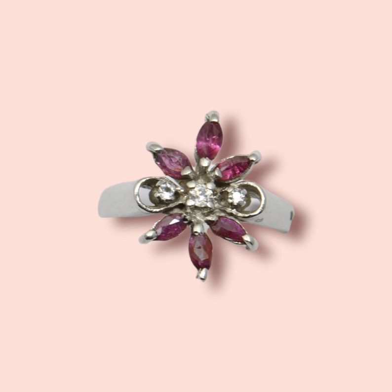 Peut inclure: Une bague en argent avec un motif de fleur orné de pierres précieuses roses et de diamants clairs.