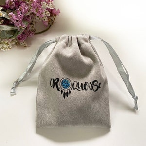 May include: A gray velvet drawstring bag with the text "IROQUOISE" printed in black with a blue and white dreamcatcher design.