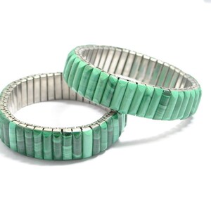 May include: Two green malachite stone bracelets with a silver metal expandable band.