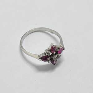 May include: A silver ring with a cluster of pink and white gemstones set in a starburst design.