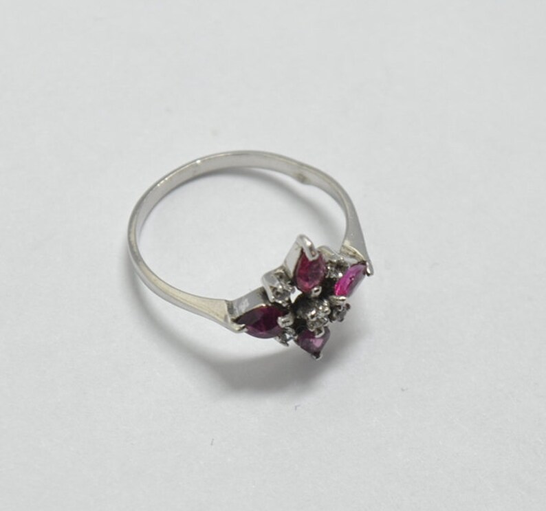 May include: A silver ring with a cluster of pink and white gemstones set in a starburst design.