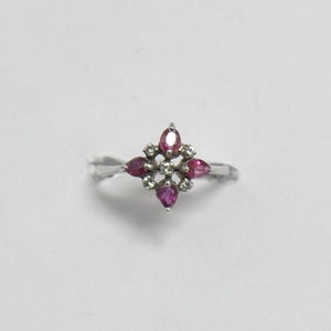 May include: A silver ring with a cluster of pink gemstones and smaller white gemstones set in a starburst design.
