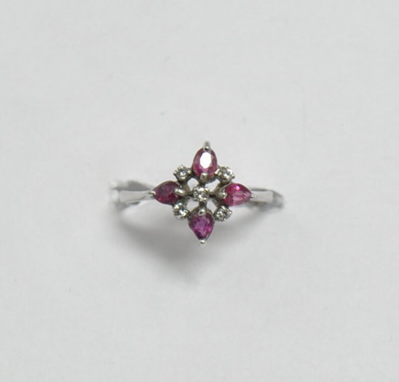 May include: A silver ring with a cluster of pink gemstones and smaller white gemstones set in a starburst design.