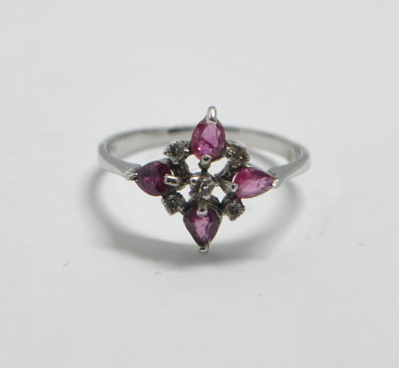 Peut inclure: Une bague en argent avec un groupe de pierres précieuses roses et de plus petites pierres précieuses blanches dans un motif en étoile.