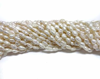 White freshwater pearls on a thread for crafting, baroque rice grain shape